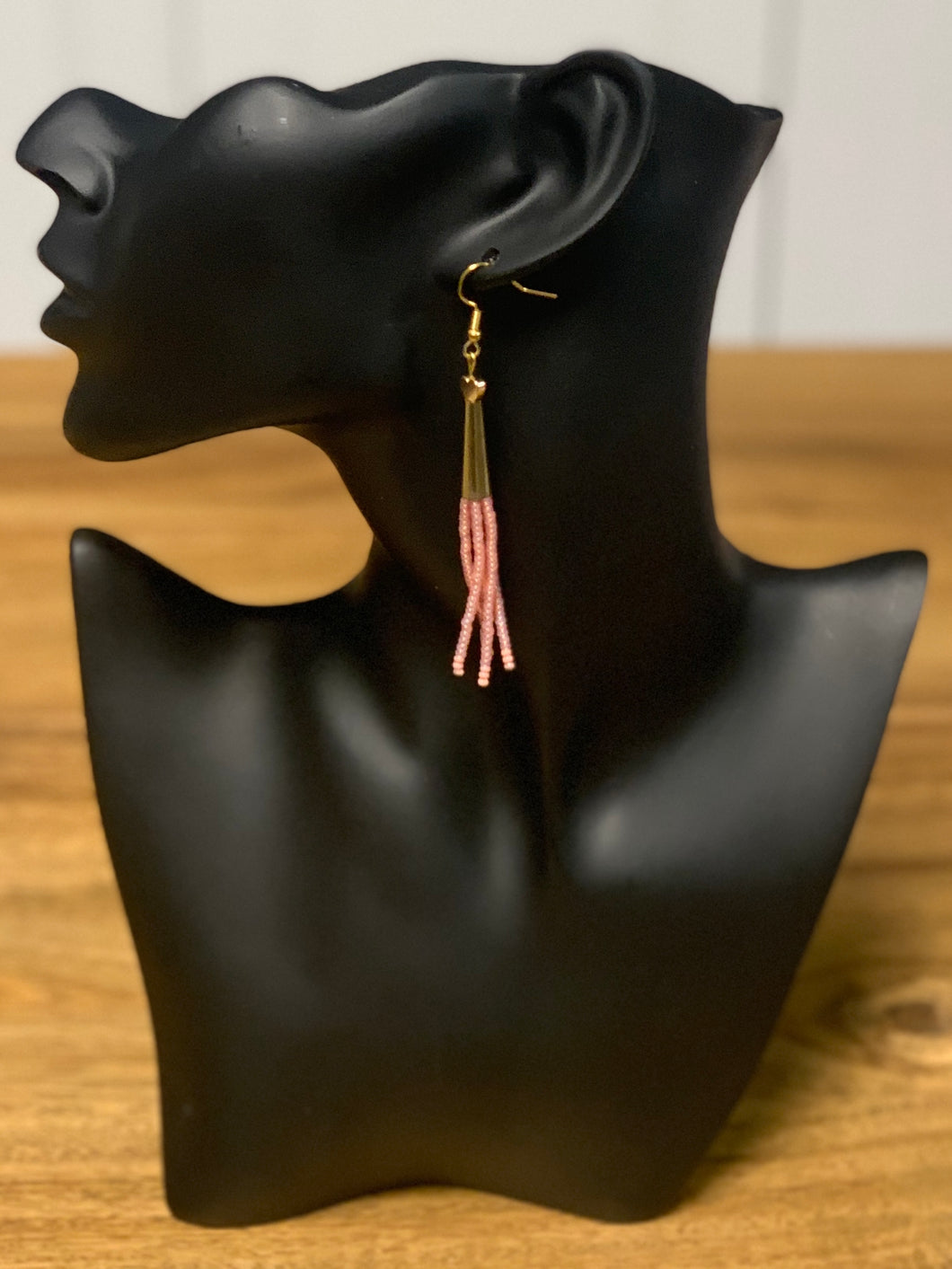 Dangling gold earrings with five strands of dangling pink beads.